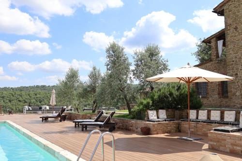 a patio with chairs and an umbrella next to a pool at Podere Cavalbianco in Ciggiano