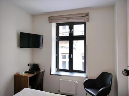 a room with a window and a chair and a desk at Hotel Jomfru Ane in Aalborg
