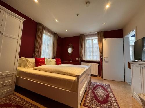 a bedroom with a large bed with red walls at Hotel & Café Schachtenburg in Schlitz