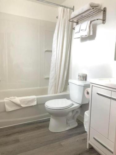 a white bathroom with a toilet and a bath tub at Canterbury Inn in Invermere