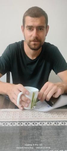 a man sitting at a table holding a coffee cup at Gerards Home stay Fortkochi in Cochin