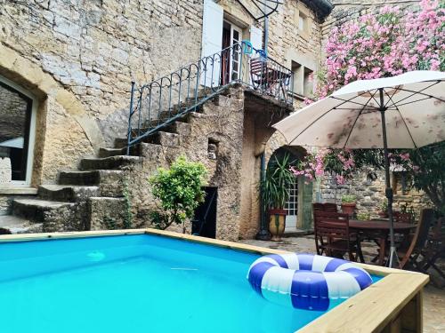 - une piscine avec un parasol à côté d'un bâtiment dans l'établissement La Maison De Thomas, à Arpaillargues-et-Aureillac