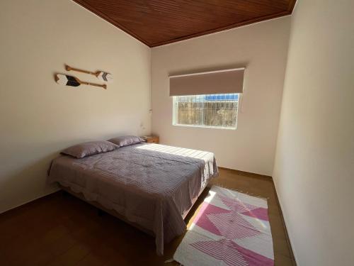 a small bedroom with a bed and a window at Casa Aconchego in Ubatuba