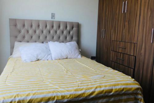 a bed with a yellow and white striped comforter and pillows at Independiente Minidepa Yanahuara in Yanahuara