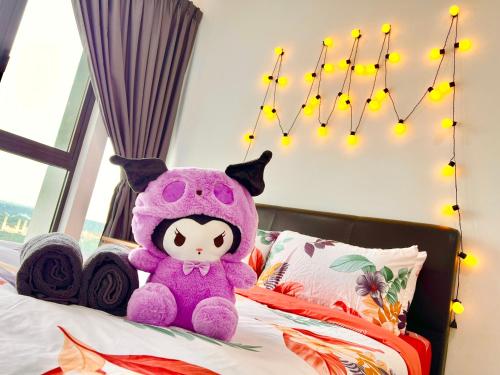 a purple teddy bear sitting on a bed with lights at Legoland-3mins Drive KUROMI FAMIY SUITE in Iskandar Puteri
