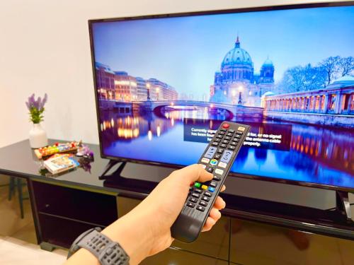 a person holding a remote control in front of a television at Legoland-3mins Drive KUROMI FAMIY SUITE in Iskandar Puteri