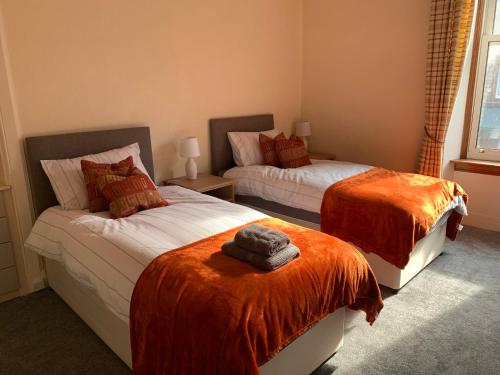 a bedroom with two beds with orange blankets at High Street 2 Bedroom Apartment in Ayr