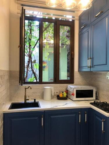 cocina con armarios azules, fregadero y ventana en Apartments MARGARITA, en Tiflis