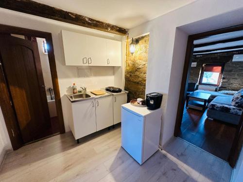 a small kitchen with white appliances and a room at Casa bunicilor in Nădăştia de Sus