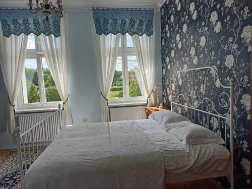 a bedroom with a bed with blue and white wallpaper at Dom Gościnny Ogłuszka in Pilec