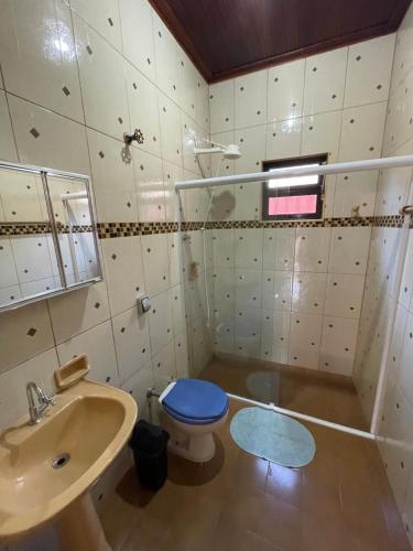 a bathroom with a blue toilet and a sink at Casa Aconchego in Ubatuba