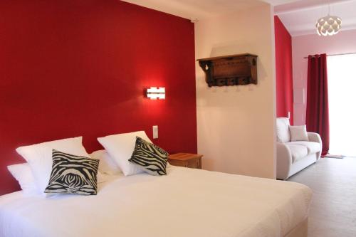une chambre avec un lit blanc avec un mur rouge dans l'établissement Suite Fleur de Cerisier, à Gordes