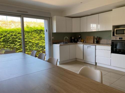 une cuisine avec des armoires blanches et une table et des chaises dans l'établissement Maison Familiale Boulogne sur Mer, à Boulogne-sur-Mer