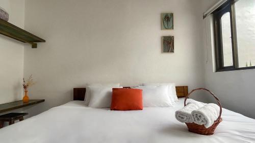 a bedroom with a white bed with a basket on it at Hotel Verona Villa de Leyva in Villa de Leyva