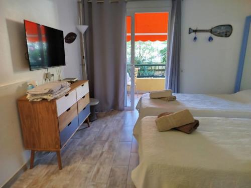 阿罗纳Appartamento los cristianos torres del sol的一间卧室配有两张床和一个带电视的梳妆台。