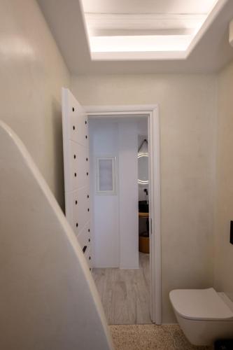 a white bathroom with a toilet and a hallway at Gallantry apartment in Galanado