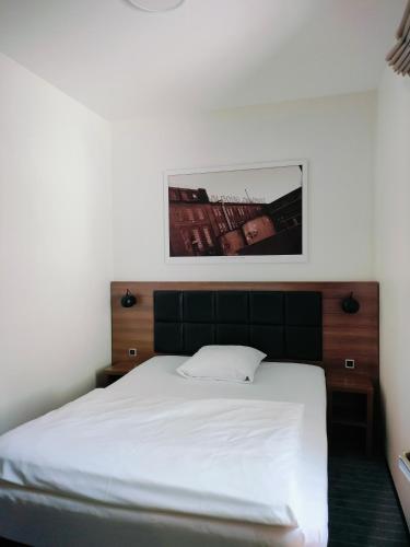 a bedroom with a white bed and a picture on the wall at Hotel Jomfru Ane in Aalborg