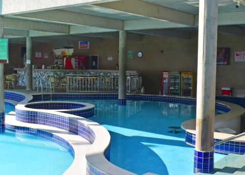 a large swimming pool with blue water in a building at Nobreza Fiori Turismo em Caldas Novas Diroma Fiori SEM ROUPAS DE CAMA BANHO E REFEIÇÕES A SEREM CONTRATADAS SEPARADAMENTE DA RESERVA in Caldas Novas