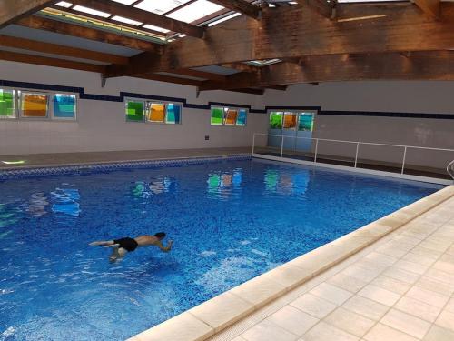 un homme nageant dans une grande piscine dans l'établissement Appartement T3 vue sur Golf, au Cap d'Agde