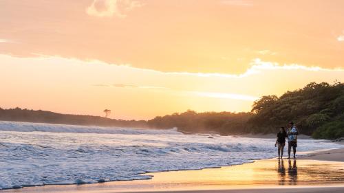 a couple walking on the beach at sunset at Punta Teonoste Beach Resort in Popoyo