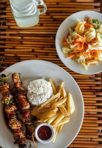 two plates of food with meat and fries and a salad at Punta Teonoste Beach Resort in Popoyo