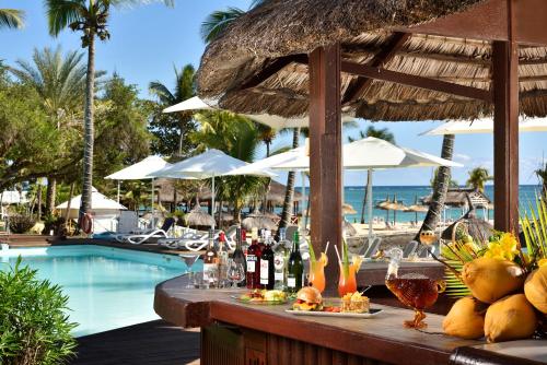 モン・ショワジーにあるCoral Azur Beach Resort Mont Choisyのスイミングプールのそばのテーブル(ドリンク、ワインのボトル付)