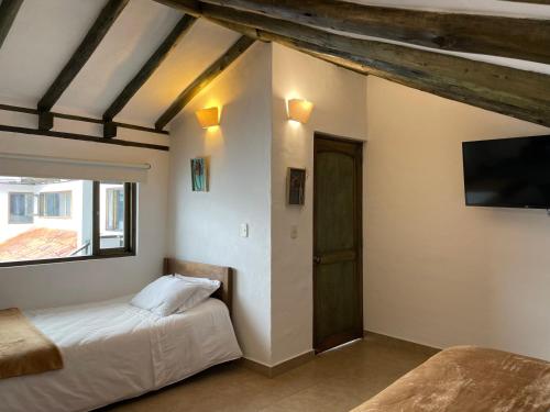 a bedroom with two beds and a flat screen tv at Hotel Verona Villa de Leyva in Villa de Leyva
