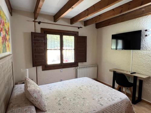 a bedroom with a bed and a desk and a television at LA CASONA DE PALMIRA in Caín