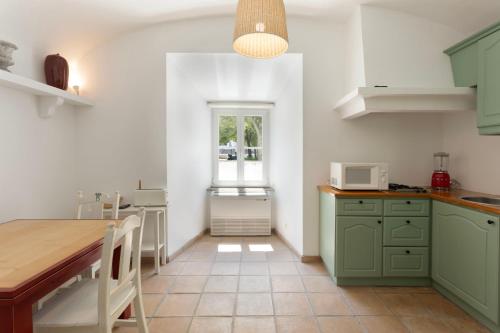 a kitchen with green cabinets and a table at Palais a Évora - appartement au coeur du patrimoine in Évora