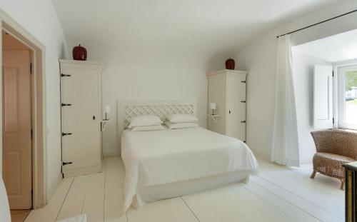 a white bedroom with a white bed and a chair at Palais a Évora - appartement au coeur du patrimoine in Évora