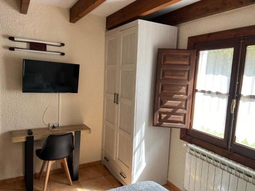 a bedroom with a desk and a tv and a window at LA CASONA DE PALMIRA in Caín