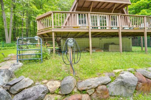 a house with a camera in the grass with rocks at A-Frame Cabin with Furnished Deck in Becket! in Becket