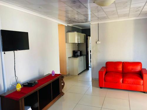 a living room with a red couch and a television at Nteto guesthouse in Dwarsloop