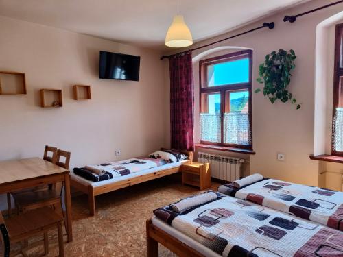 a room with two beds and a table and a window at Apartamenty i pokoje gościnne "Wacuś" in Srebrna Góra