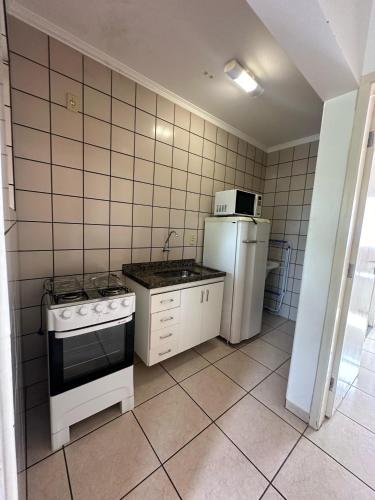 a small kitchen with a stove and a refrigerator at Nobreza Fiori Turismo em Caldas Novas Diroma Fiori SEM ROUPAS DE CAMA BANHO E REFEIÇÕES A SEREM CONTRATADAS SEPARADAMENTE DA RESERVA in Caldas Novas