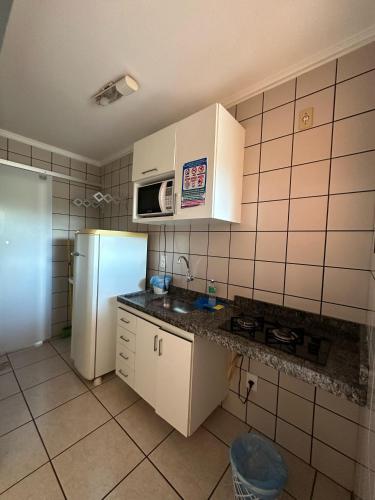 a kitchen with a refrigerator and a microwave at Nobreza Fiori Turismo em Caldas Novas Diroma Fiori SEM ROUPAS DE CAMA BANHO E REFEIÇÕES A SEREM CONTRATADAS SEPARADAMENTE DA RESERVA in Caldas Novas