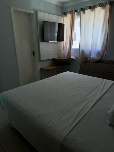 a bedroom with a large white bed and a television at Nobreza Fiori Turismo em Caldas Novas Diroma Fiori SEM ROUPAS DE CAMA BANHO E REFEIÇÕES A SEREM CONTRATADAS SEPARADAMENTE DA RESERVA in Caldas Novas