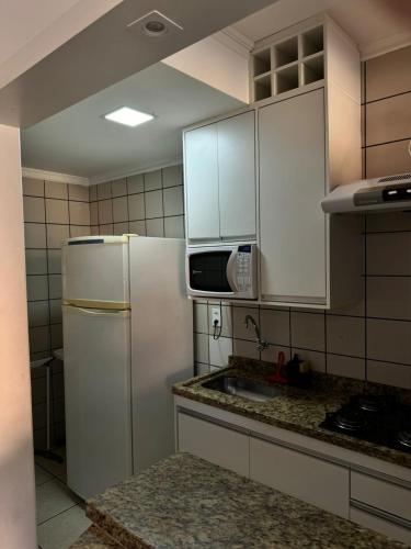 a kitchen with white cabinets and a refrigerator at Nobreza Fiori Turismo em Caldas Novas Diroma Fiori SEM ROUPAS DE CAMA BANHO E REFEIÇÕES A SEREM CONTRATADAS SEPARADAMENTE DA RESERVA in Caldas Novas