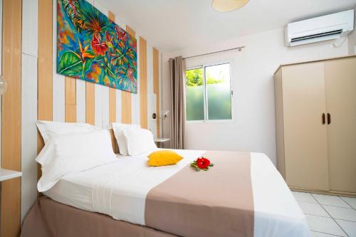 a bedroom with a white bed with a flower on it at Hôtel Village Pomme Cannelle 3 étoiles in Le Prêcheur