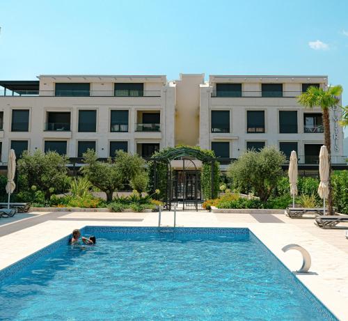 a person in a swimming pool in front of a building at Dimitris Residence in Tivat