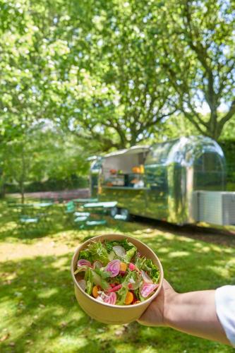 a person holding a bowl of salad with an rv in the background at Terra Nostra Garden Hotel in Furnas
