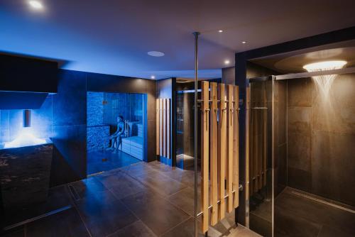 a bathroom with a walk in shower with blue lighting at Hotel Jägerhof in Colfosco