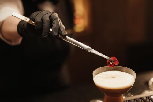 a person in black gloves holding a stick in a drink at Hotel Jägerhof in Colfosco