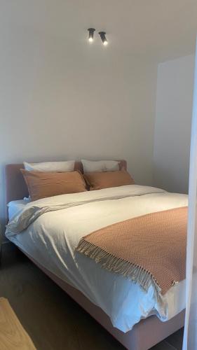a bed with white sheets and orange pillows at Orfeo Knokke in Knokke-Heist