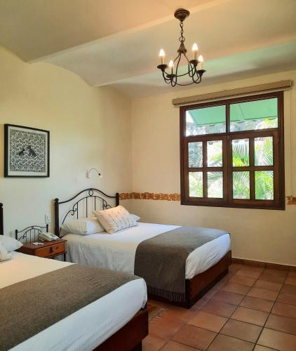 a bedroom with two beds and a window at Casa los Cantaros Hotel Boutique in Oaxaca City