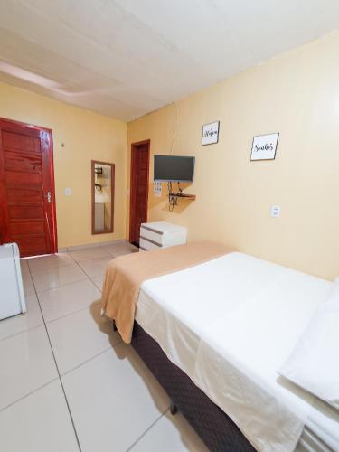 a bedroom with a bed and a tv on the wall at Babylon Village in Algodoal