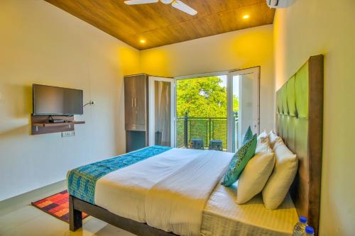 a bedroom with a bed and a large window at Beach Comforts By Balaji Inn in Calangute