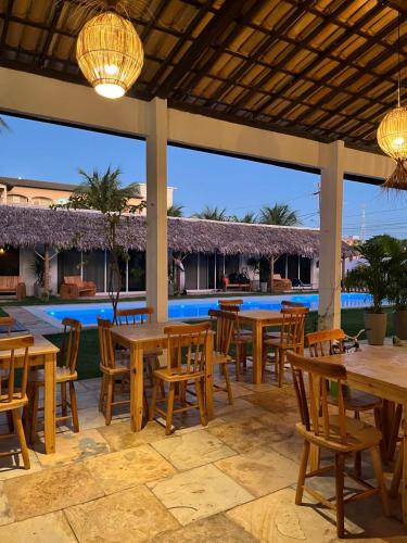 a patio with wooden tables and chairs and a pool at Pousada Vila Flow in Cumbuco