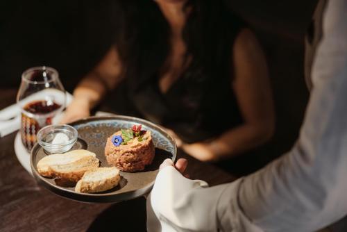a person holding a plate of food on a table at Hotel Jägerhof in Colfosco