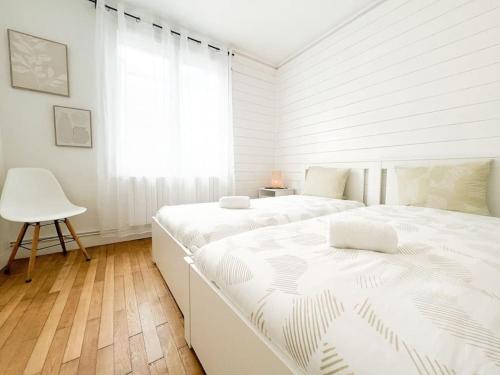 Un dormitorio blanco con dos camas y una silla. en T2 Jardin, Centre, Gare, 5'plage, en Saint-Nazaire